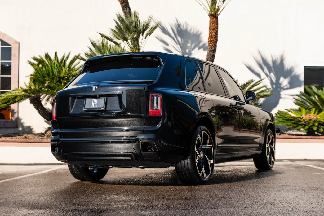 Black luxury SUV parked on a street with palm trees in the background