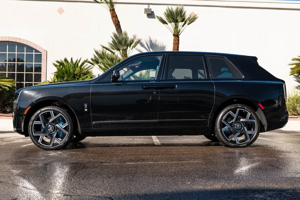 Black luxury SUV parked on a wet road with palm trees in the background