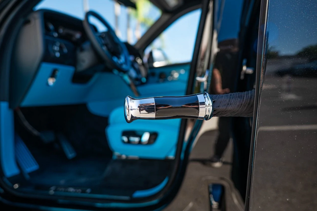 Close-up of a car door handle with interior details, including steering wheel and dashboard.