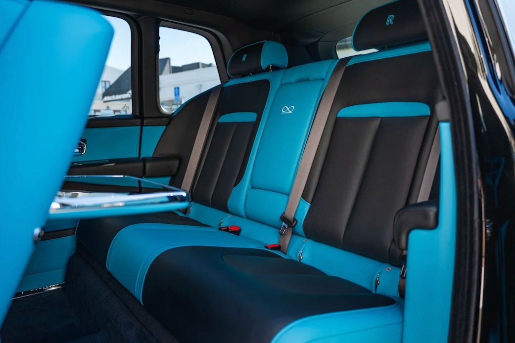 Blue and black car interior with visible seat belts and door open.