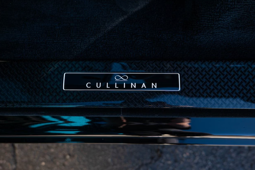 Close-up of a car badge with 'Cullinan' text on a dark textured background