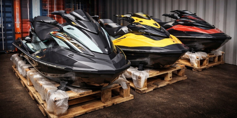 Four jet skis on wooden pallets in a storage area.