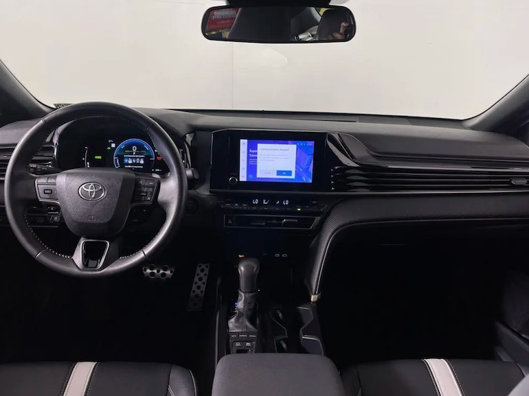 Car interior with steering wheel, dashboard, and touchscreen display.