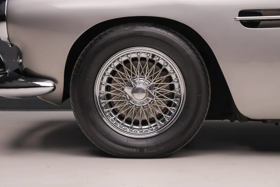 Close-up of a car wheel with a shiny hubcap on a gray background