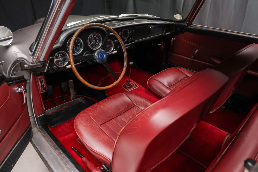 Vintage car interior with red leather seats and dashboard details.