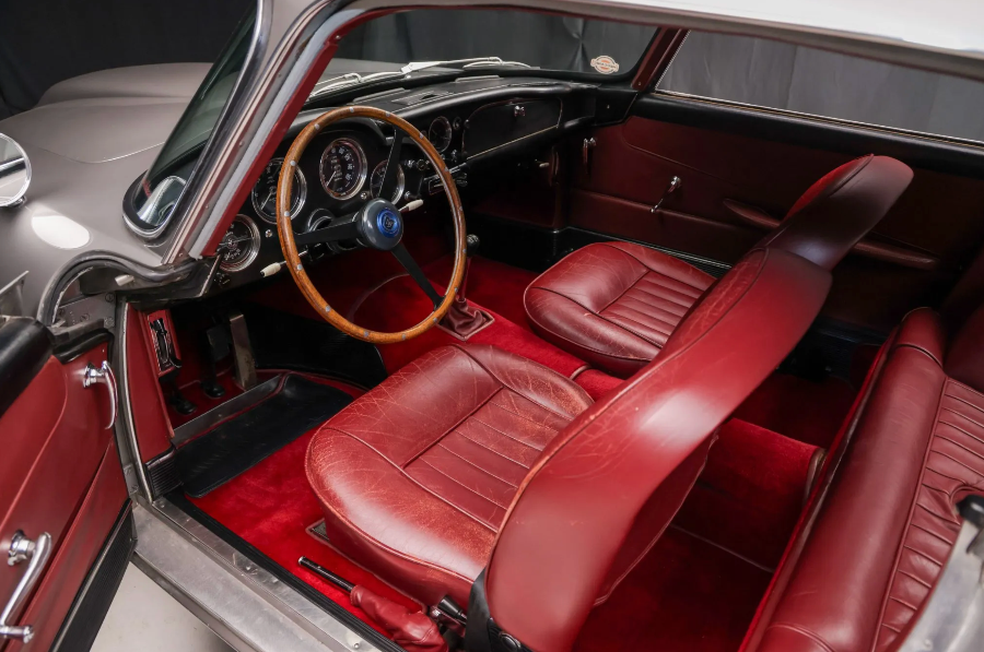 Interior of a classic car with red leather seats and dashboard.