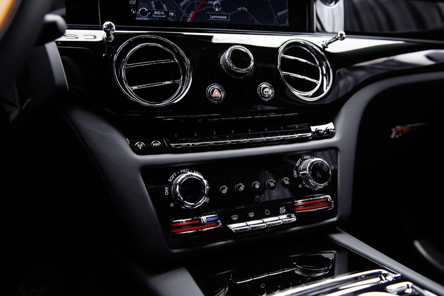 Close-up of a luxury car's dashboard with air vents and control panel.