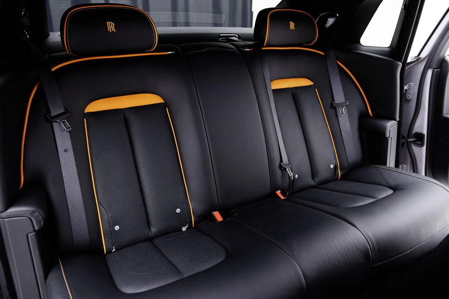 Black car interior with orange accents and Rolls-Royce logo.