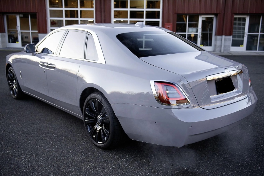 Silver luxury car parked on a street with a building in the background