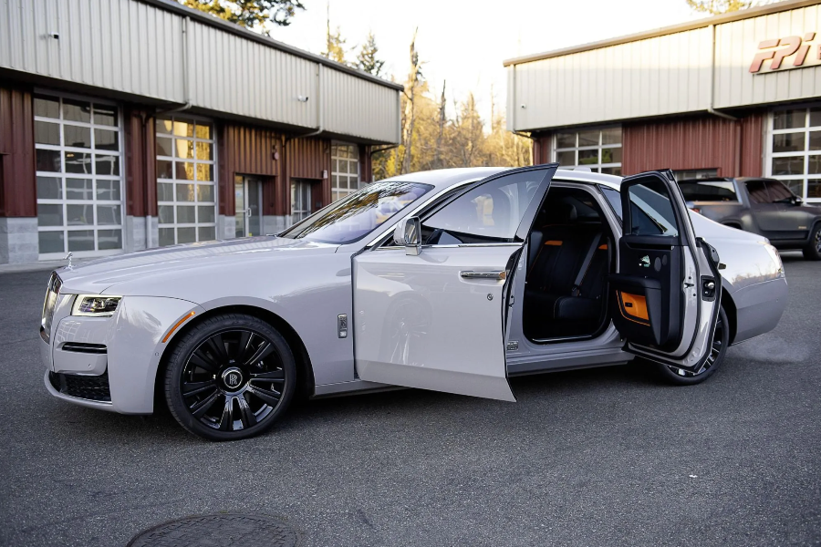 White luxury car with open door parked in front of a building