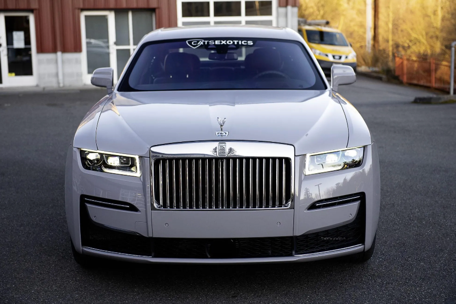 Front view of a luxury car with a visible brand logo on a road.