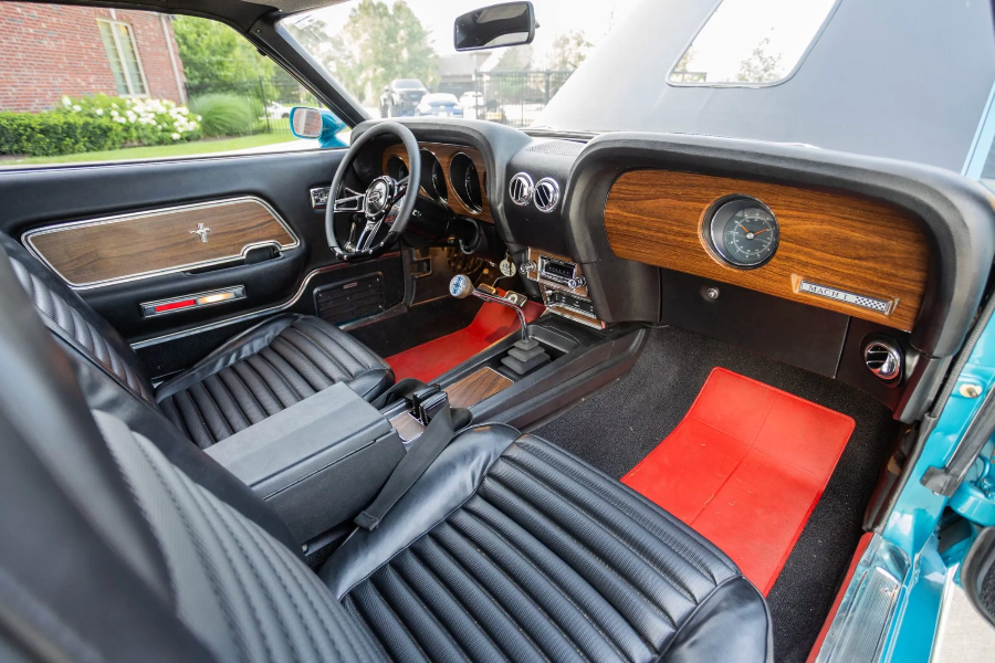 Close-up of a classic car's interior with wooden dashboard and red accents.