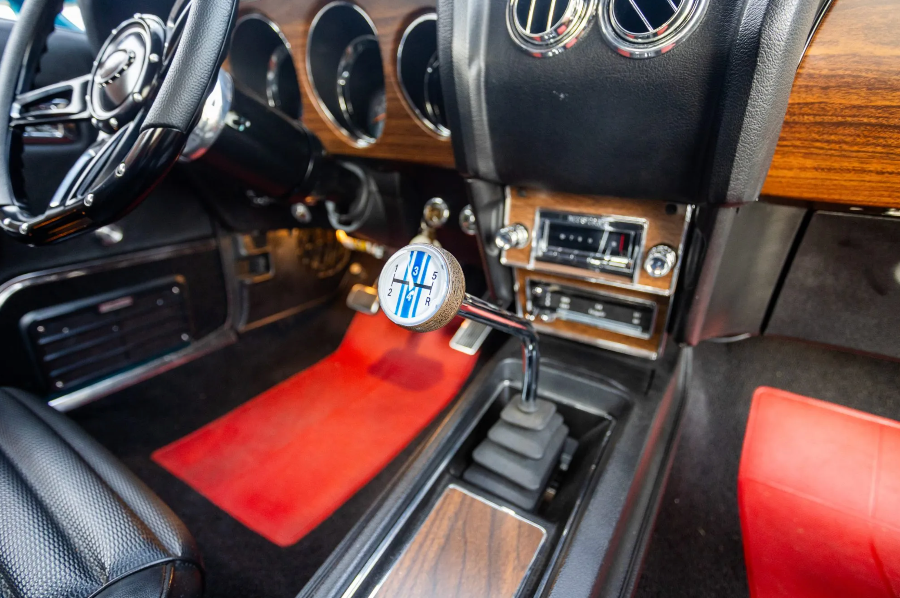 Close-up of a car's interior with a manual gear shift and wooden dashboard.