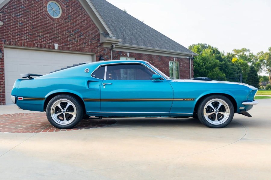 Blue muscle car parked in front of a brick house