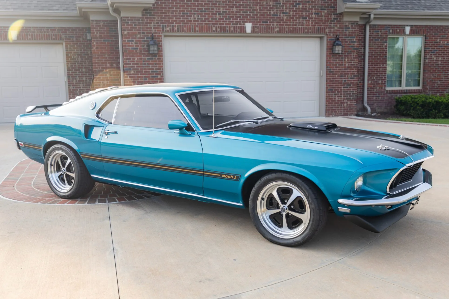 Blue muscle car parked in front of a brick house