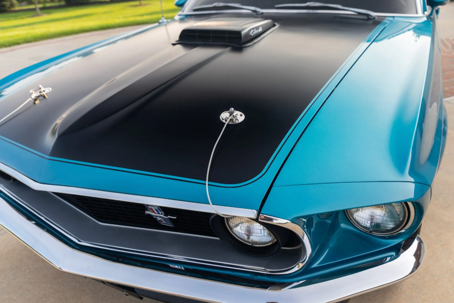 Close-up of a blue and black muscle car with a prominent hood scoop.