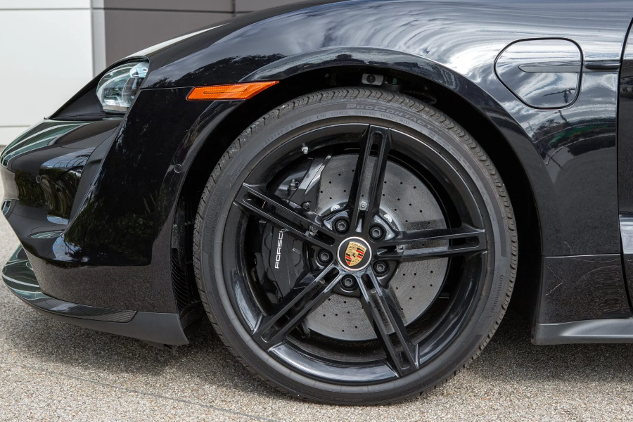 Close-up of a black Porsche car wheel with visible logo.