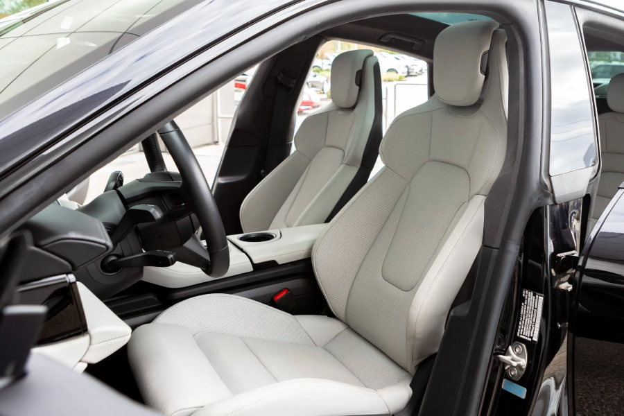 Close-up of a car's interior with white seats and black door panels.