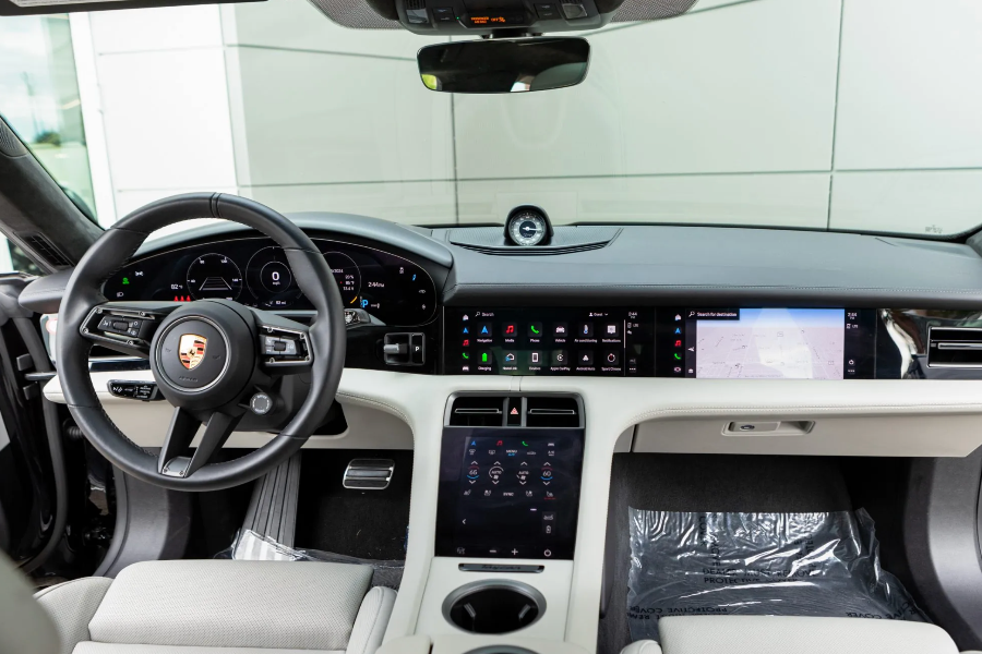 Car interior with steering wheel and dashboard featuring digital displays.