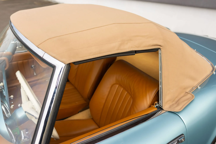Close-up of a vintage car's interior with beige leather seats and roof.