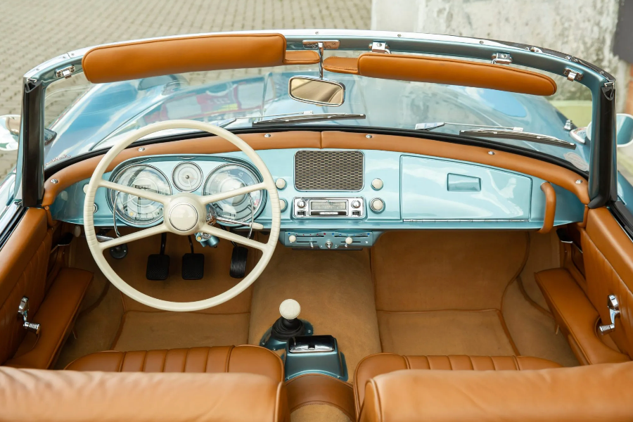 Vintage car interior with brown leather seats and dashboard.