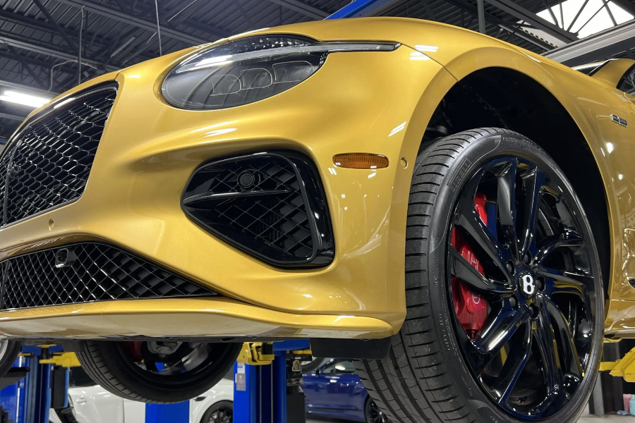 Yellow Bentley car on a lift in a garage