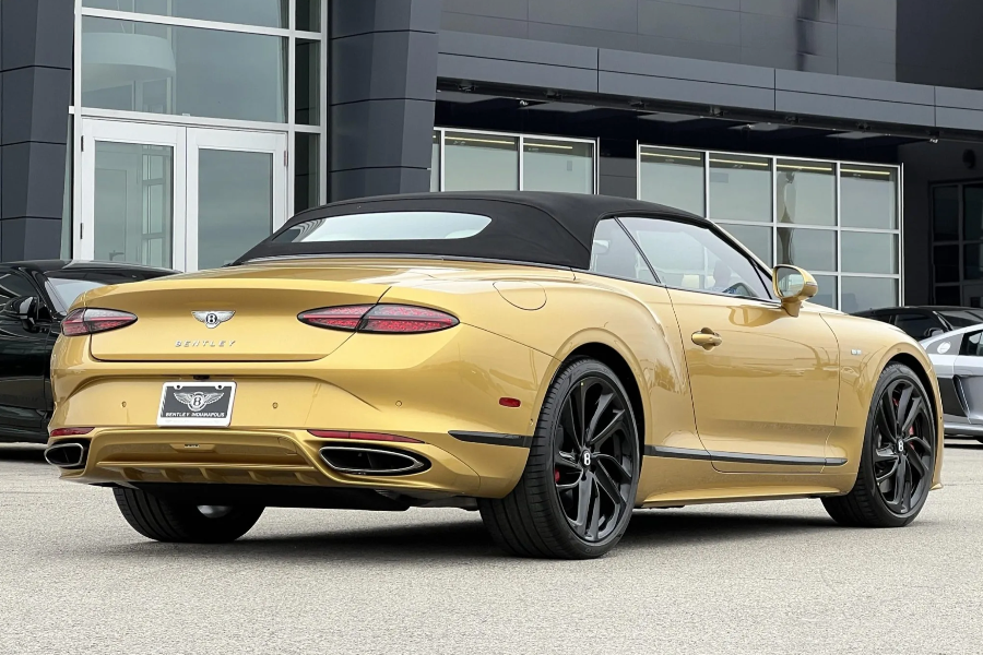 Gold convertible car parked in front of a modern building