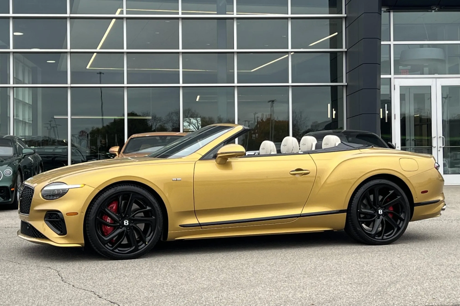 Gold convertible car parked in front of a glass building