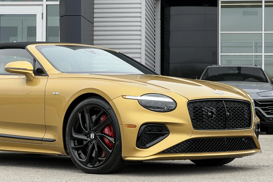 Gold Bentley convertible parked in front of a building