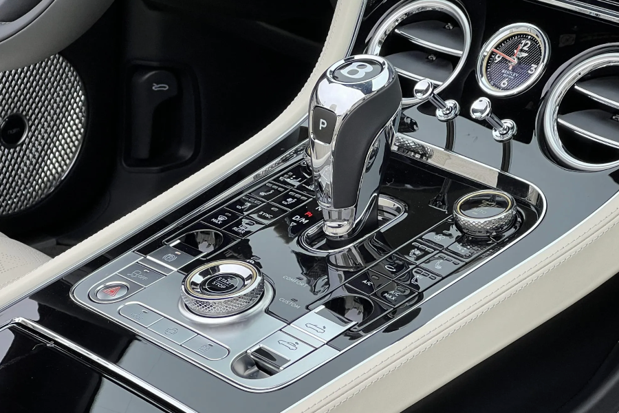 Car gear shift lever with surrounding controls in a luxury vehicle interior.