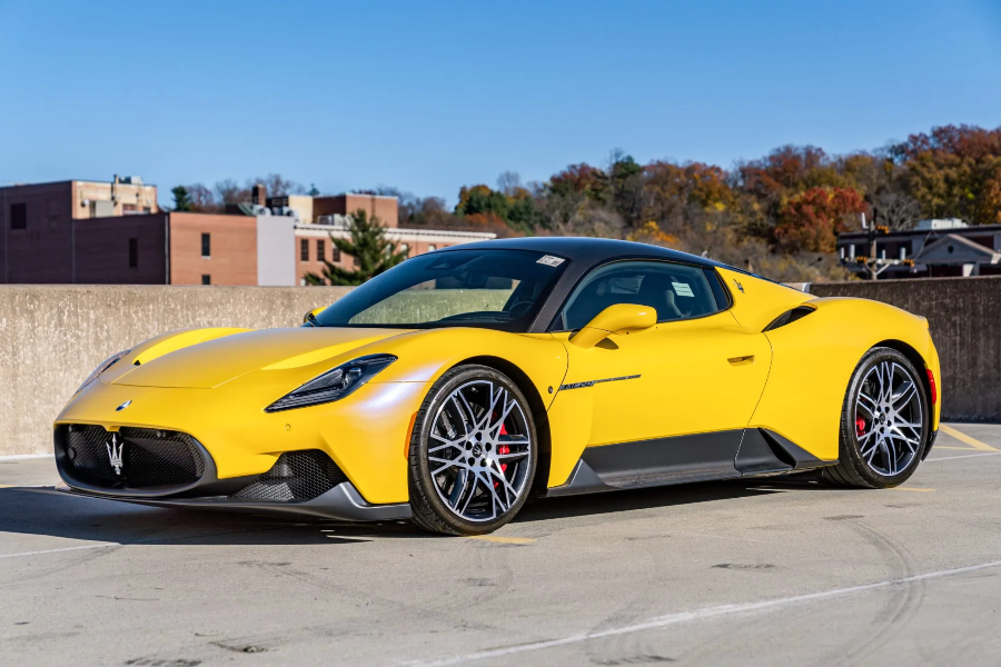 Yellow sports car on a track with buildings and trees in the background