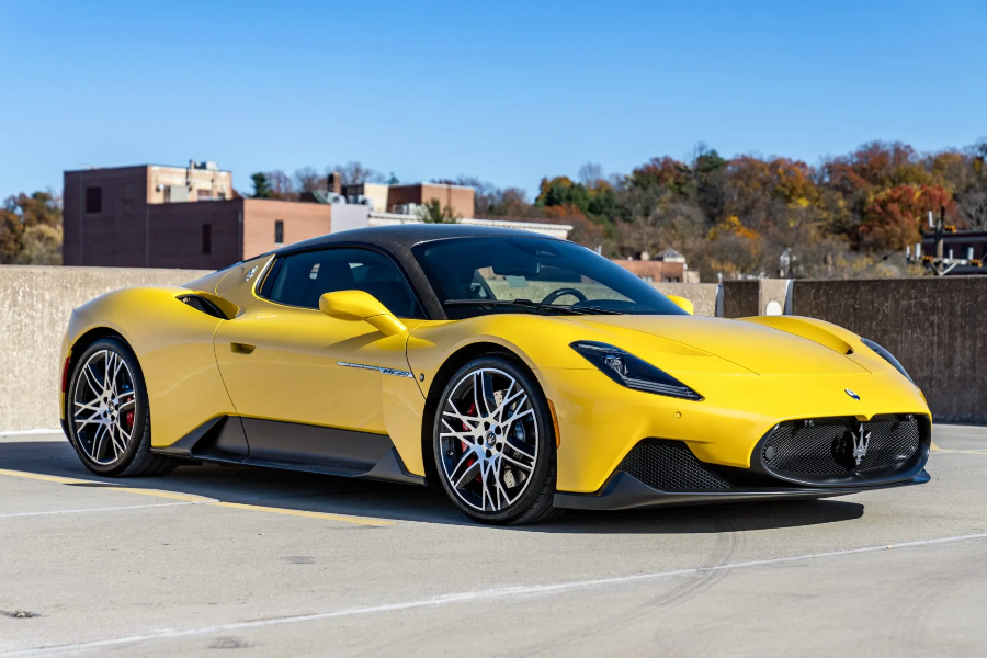 Yellow sports car on a road with buildings and trees in the background