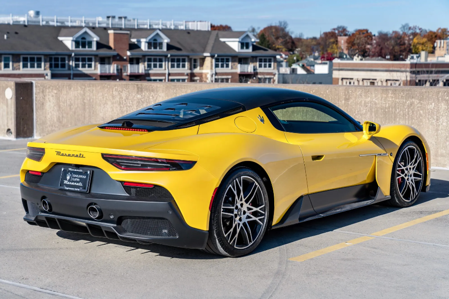 Yellow sports car parked in a parking lot with buildings in the background