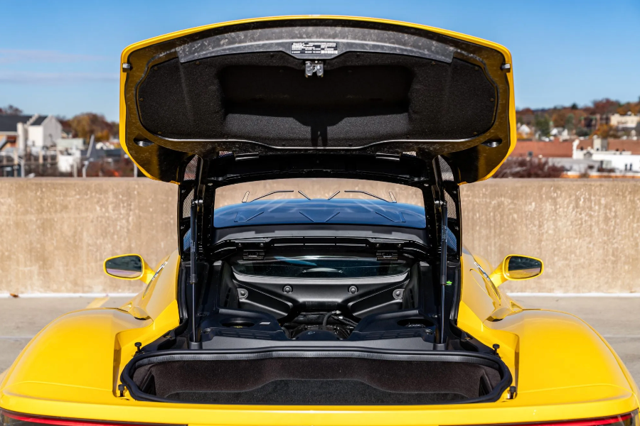 Yellow sports car with open trunk on a city street