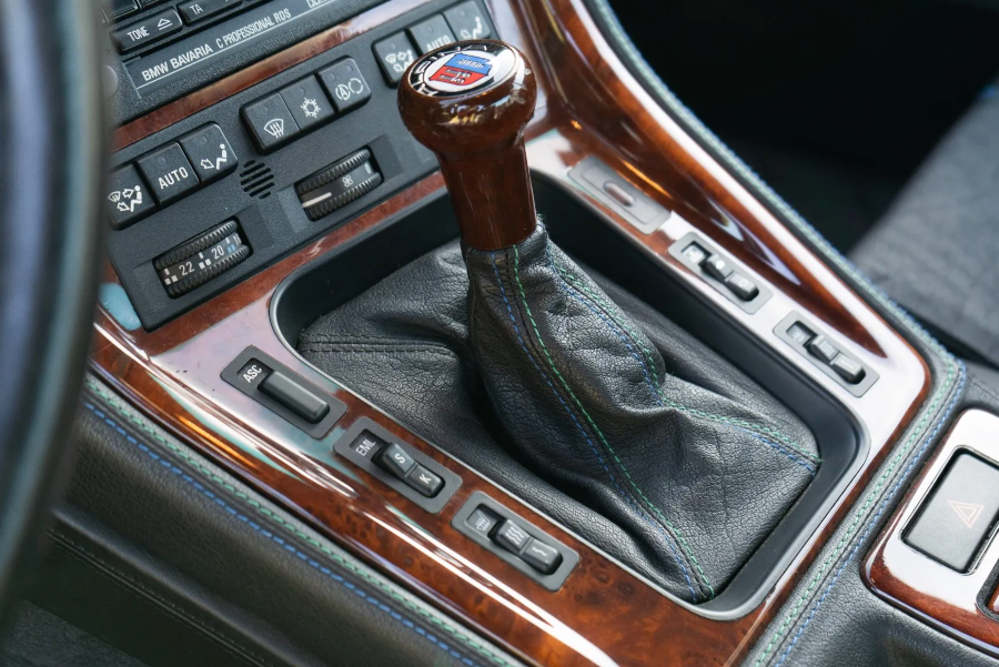 Close-up of a car's gear shift lever with wooden accents and visible BMW logo.