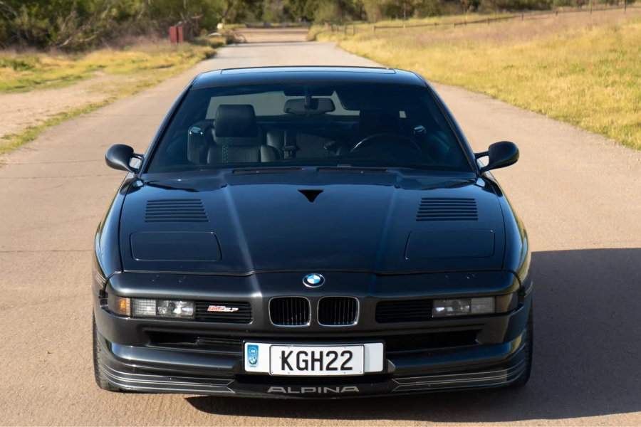 Black BMW car on a rural road with greenery in the background