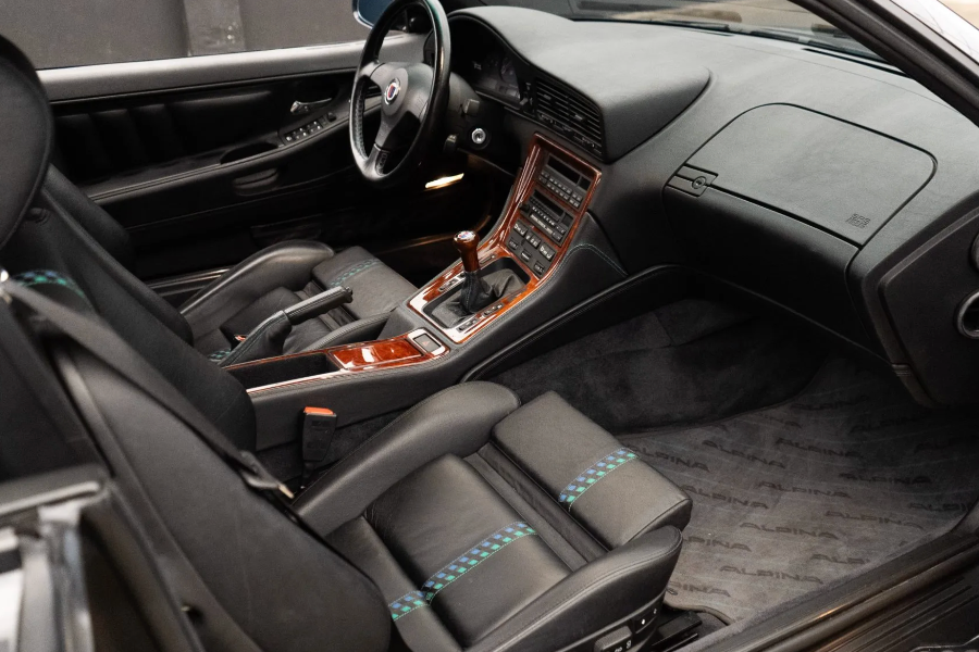 Car interior with black leather seats and wooden dashboard.