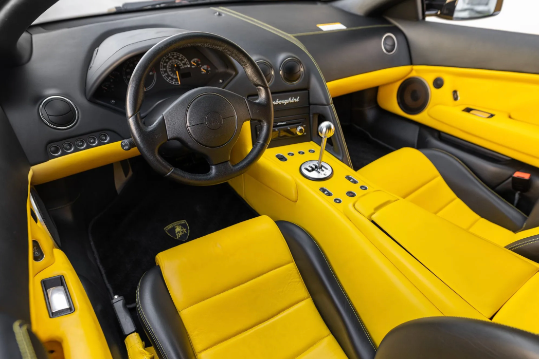 Yellow and black car interior with steering wheel and dashboard.