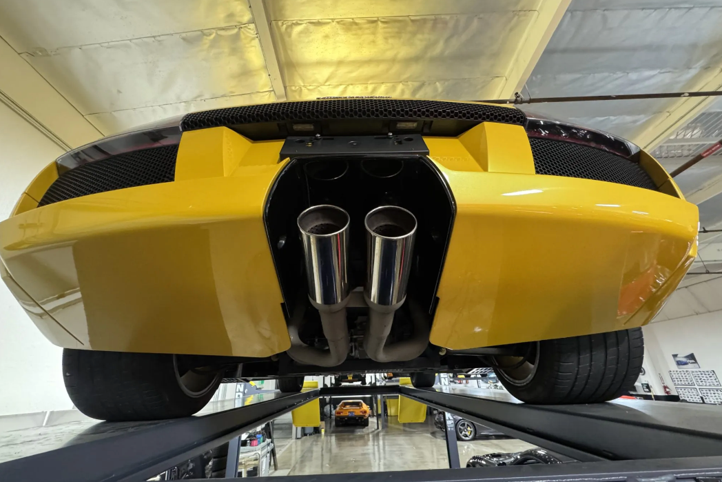 Yellow sports car with a dual exhaust system on a lift in a garage.