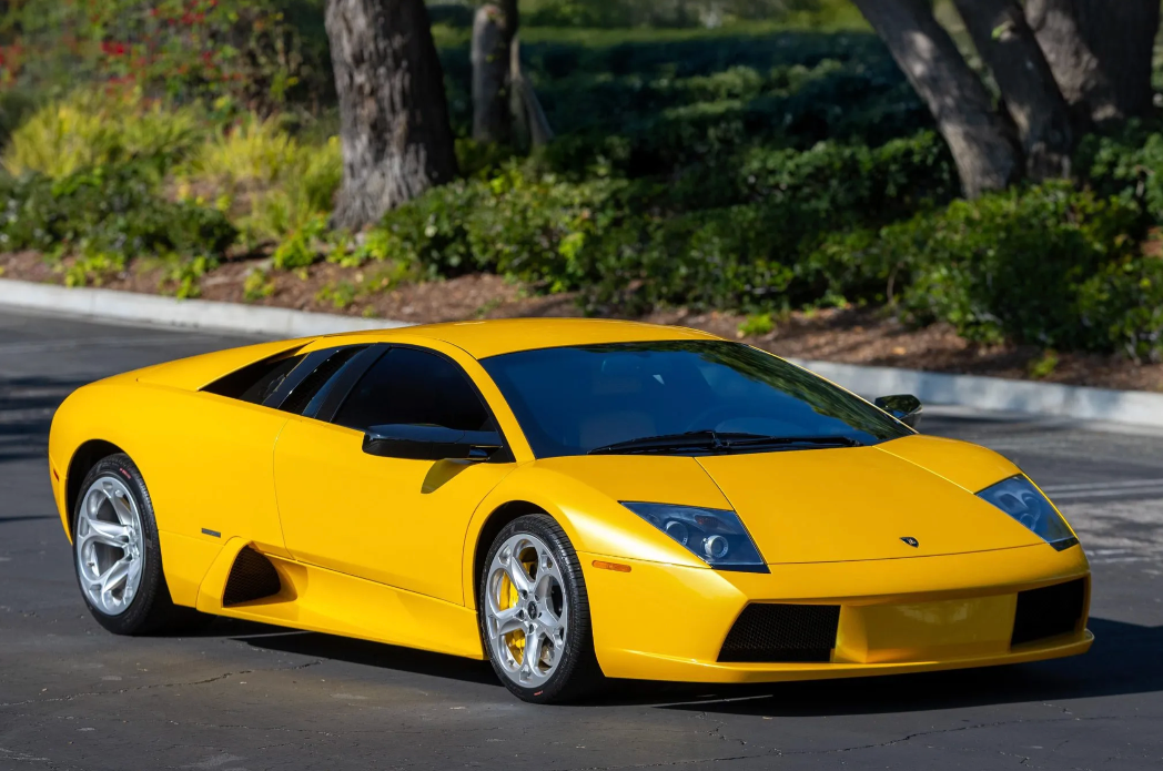 Yellow sports car on a road with greenery in the background