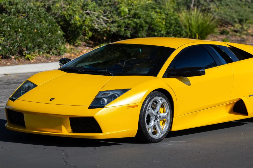 Yellow sports car on a road with greenery in the background