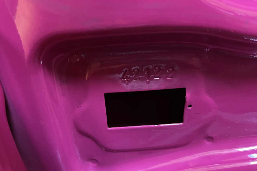 Close-up of a pink plastic object with a black rectangular label on a white background