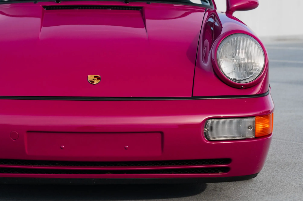 Close-up of a red Porsche car with the logo on the hood.