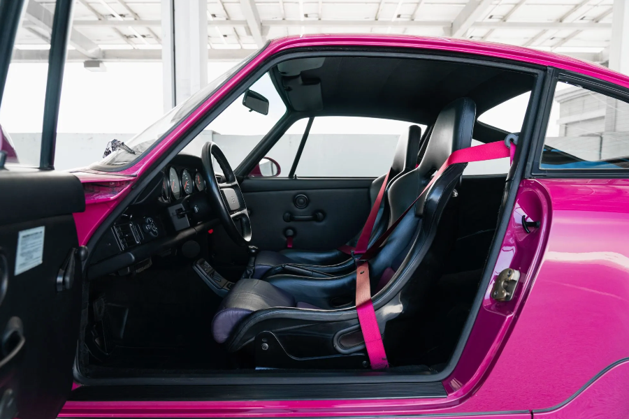 Interior of a pink car with black seats and dashboard.