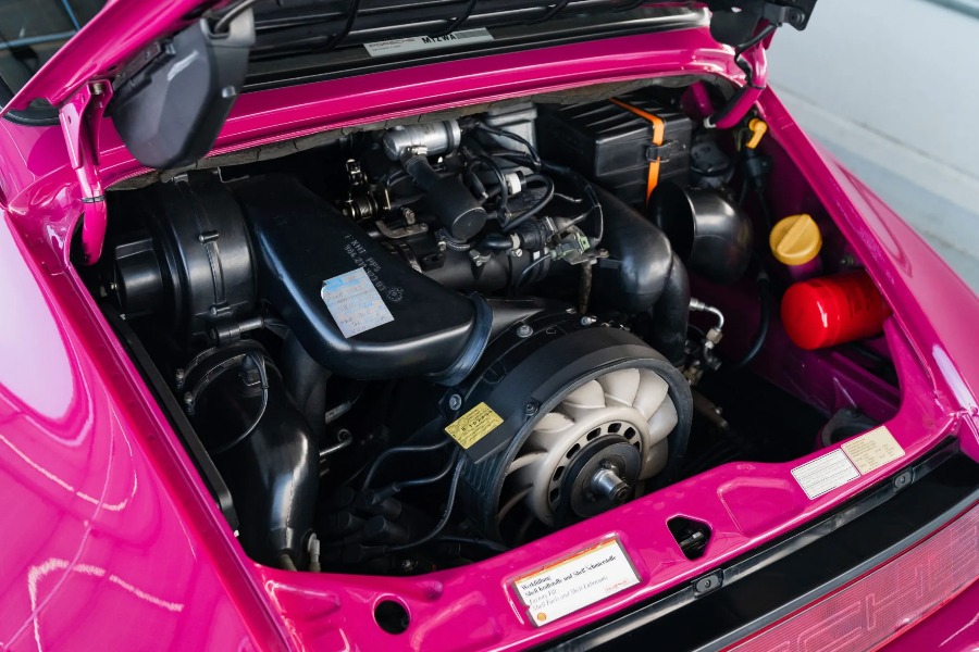 Engine compartment of a pink car with visible components.