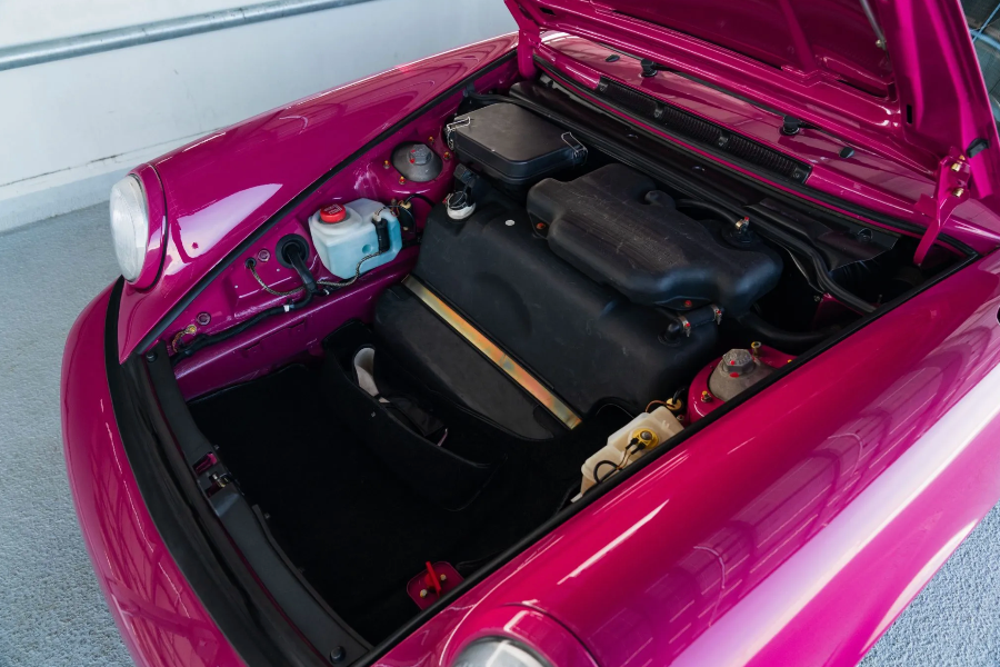 Open trunk of a pink car revealing mechanical components.